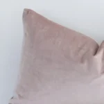A close up image of this solid-coloured rectangle cushion. The image shows details of its velvet fabric and dusty pink colour.