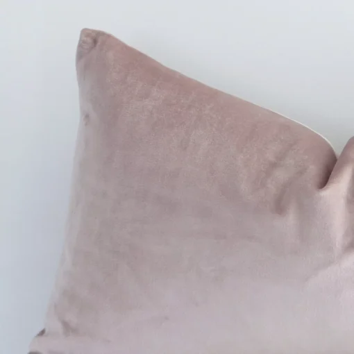 A close up image of this solid-coloured rectangle cushion. The image shows details of its velvet fabric and dusty pink colour.
