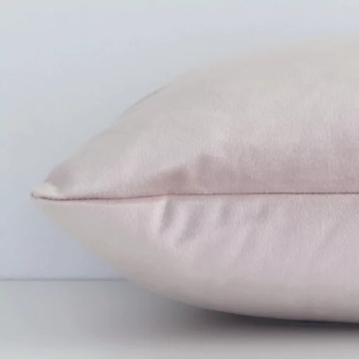 Side shot showing the seam of this rectangle dusty pink cushion that features a solid-coloured motif on its velvet material.