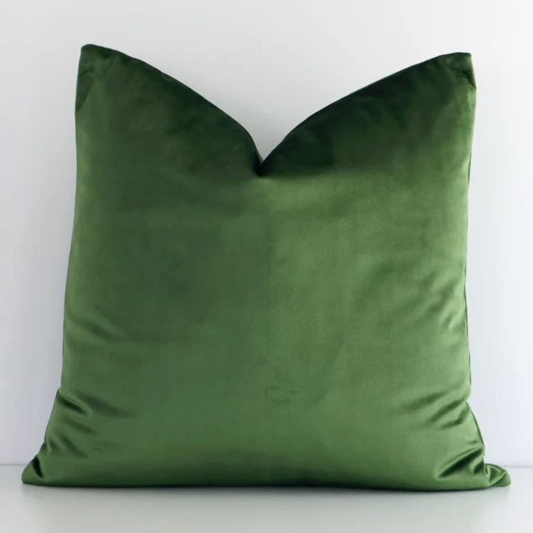 A pretty solid-coloured velvet cushion cover is shown against a white wall. It features a square shape and a forest green colour finish.