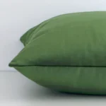 Horizontal edge view of front and back panels of a solid-coloured velvet cushion in a square size and with forest green colouring.