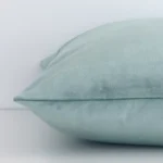 Square solid-coloured cushion in mint green colour laying flat. The viewpoint highlights the seams of the velvet fabric.