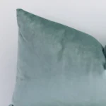 The corner of this mint green velvet cushion is shown close up. The finer detail of its rectangle design and solid colour finish can be seen.