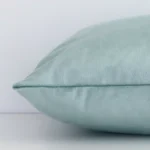 Mint green rectangle cushion cover laid on its back side. It is made of velvet material.
