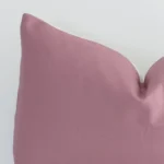 A linen rectangle cushion’s corner has been enlarged in this shot. The detail of the solid-colour blush colour is visible.