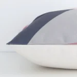 Square colourful cushion laid flat. This view shows the geometric style and linen fabric from side on.