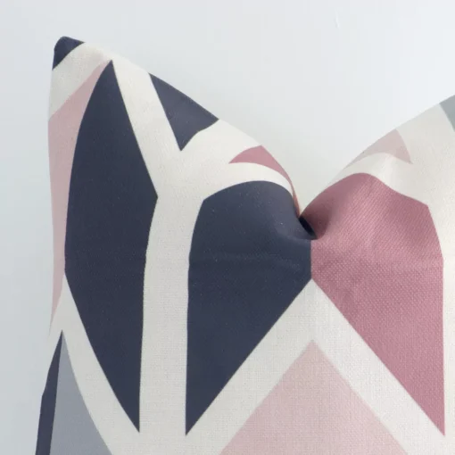 Square geometric cushion in colourful print sitting upright in front of a white wall. It has been made from a quality linen material.