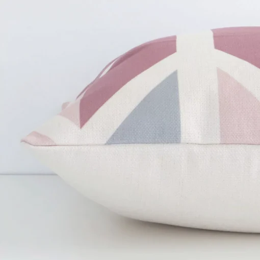 Colourful geometric cushion cover laying sideways against white wall. The square size and linen material are shown highlighting the seams.