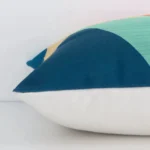 Geometric colourful cushion laid horizontally. This perspective shows the edge of the linen fabric and its square shape.