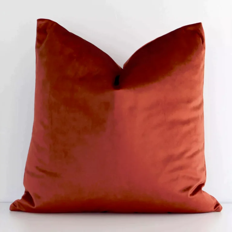 An eye-catching velvet square cushion cover featuring a hue that is rust. It has an elegant solid-coloured style.