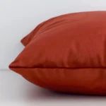 Lateral view of front and back panels of this solid-coloured velvet cushion cover in a sqaure size and with rust colouring.
