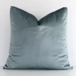 Sage Green solid-coloured cushion cover sits against a white wall. It is constructed from a superior looking velvet material and has square dimensions.