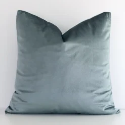 Sage Green solid-coloured cushion cover sits against a white wall. It is constructed from a superior looking velvet material and has square dimensions.