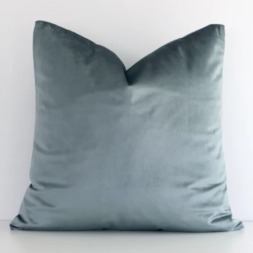 Sage Green solid-coloured cushion cover sits against a white wall. It is constructed from a superior looking velvet material and has square dimensions.