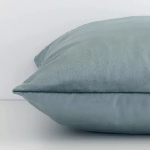 Lateral viewpoint of this velvet square cushion. The solid-coloured design and sage green colour are shown from the side showing the front and rear panels.