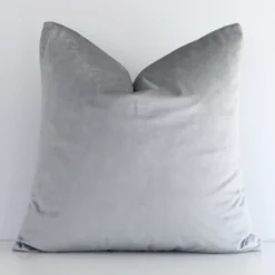 Square solid-coloured cushion cover in silver colour sitting upright in front of a brick wall. It has been made from a quality velvet material.