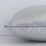 A sideways perspective of this solid-coloured velvet cushion. The positioning shows the border of the rectangle shape and the silver colour.
