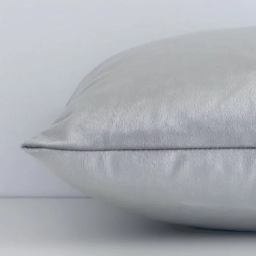 A sideways perspective of this solid-coloured velvet cushion. The positioning shows the border of the rectangle shape and the silver colour.