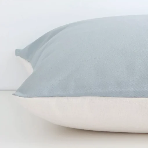 The edge of this linen large cushion in soft teal is shown. The shot shows the solid colour design and the front and rear panels.
