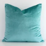 Spearmint velvet cushion cover features prominently against a white wall. It is a square design.