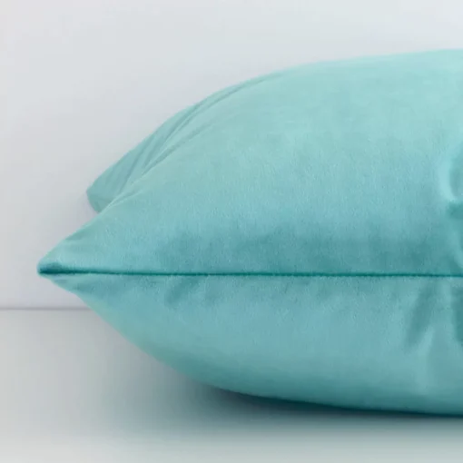 Square solid-coloured cushion cover in spearmint colour sitting flat. The sideways viewpoint shows the seams of the velvet material.