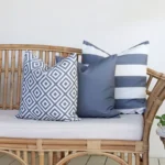 Grey outdoor cushions from the set of 3 Byron couch cushions are arranged neatly on a rattan seat.