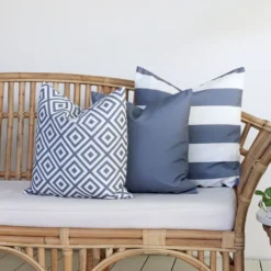 Grey outdoor cushions from the set of 3 Byron couch cushions are arranged neatly on a rattan seat.