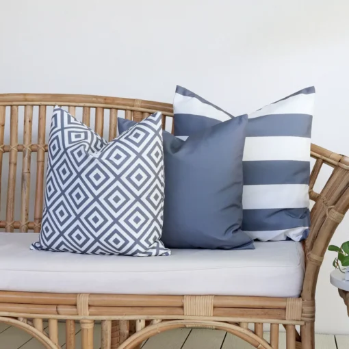 Grey outdoor cushions from the set of 3 Byron couch cushions are arranged neatly on a rattan seat.