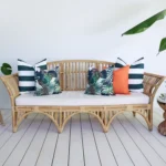 A rattan seat in bright living area displays a set of 5 Byron floral outdoor cushions.
