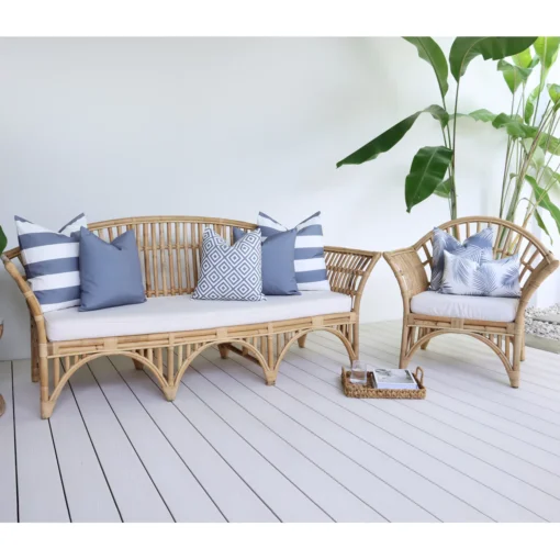 7 grey cushions with various designs arranged on rattan seats in front of a white wall.