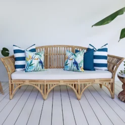 A rattan seat in front of a white wall is styled with a set of 5 green outdoor cushions from Byron collection.