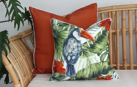 Arranged tropical outdoor cushions on a cane and beige seat.