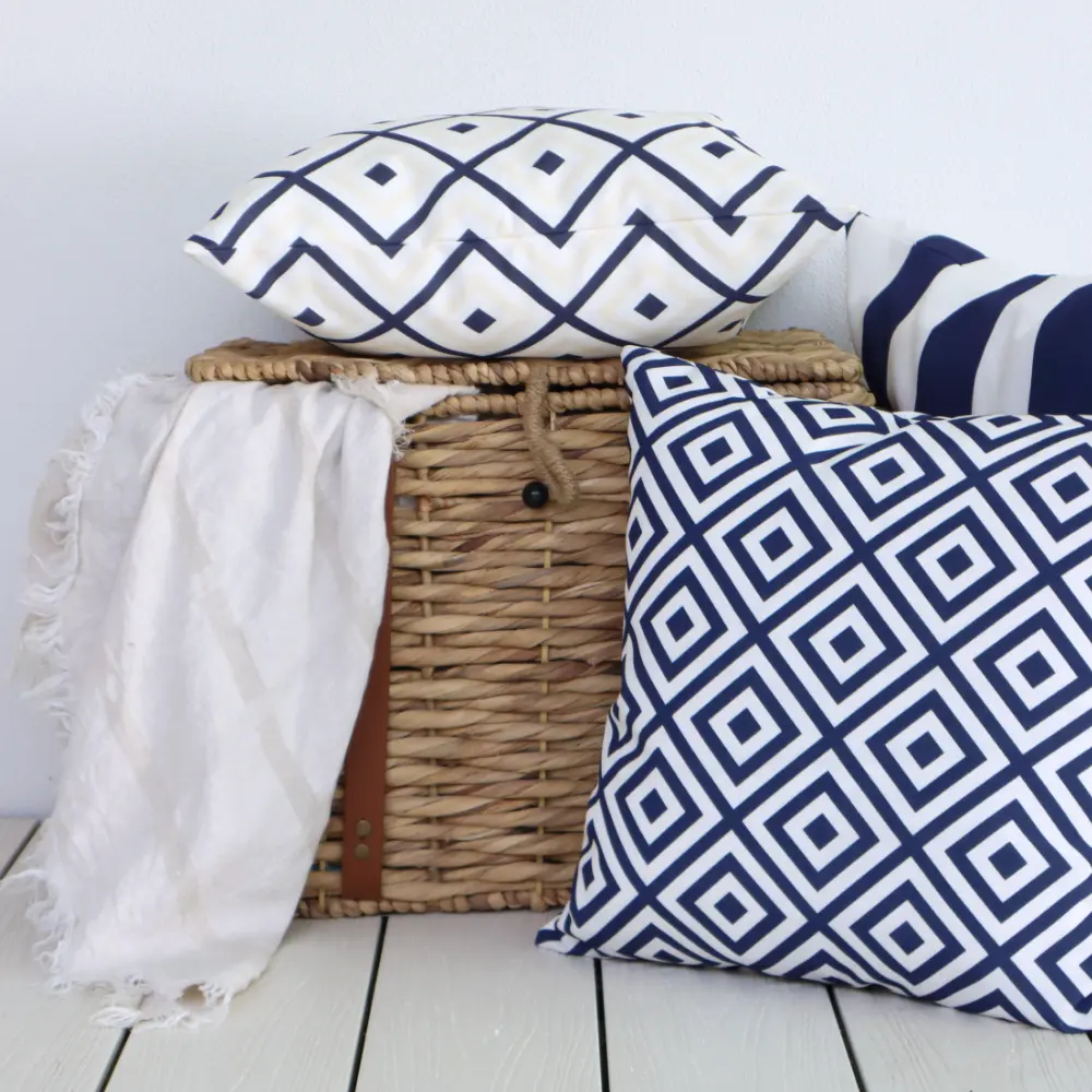 A woven basket with an outdoor cushion set styled on and around it.