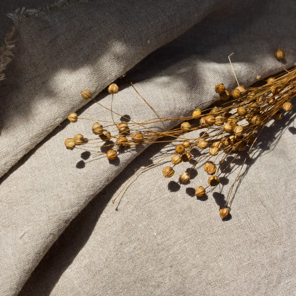 Natural linen fabric roll with small bundles of flax plant.