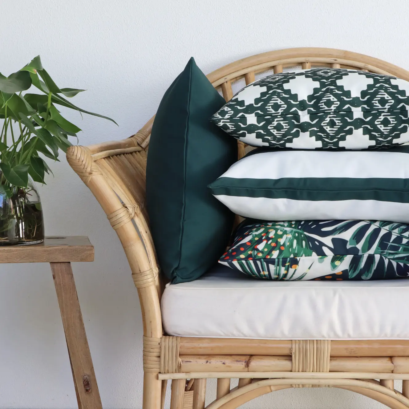 A simple styled arrangement of outdoor cushions with some plants in the shot.