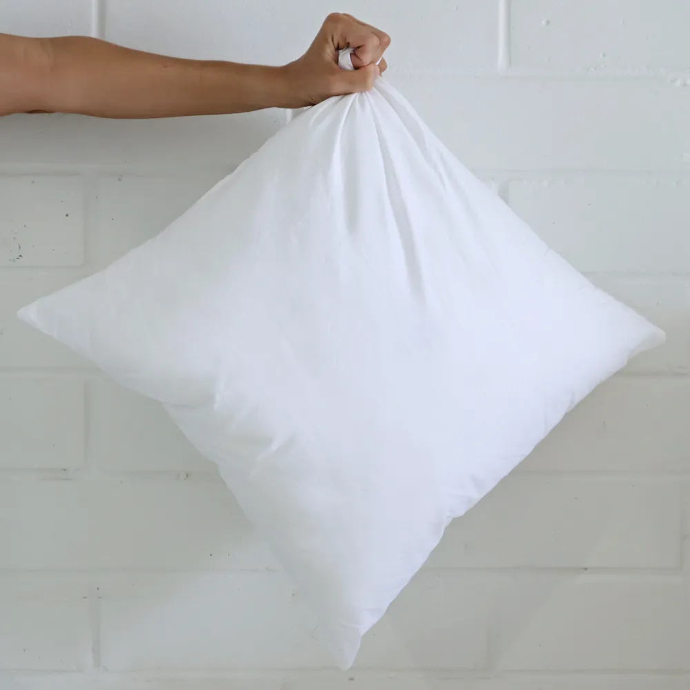 A square insert is being held out by a hand in front of a white wall.