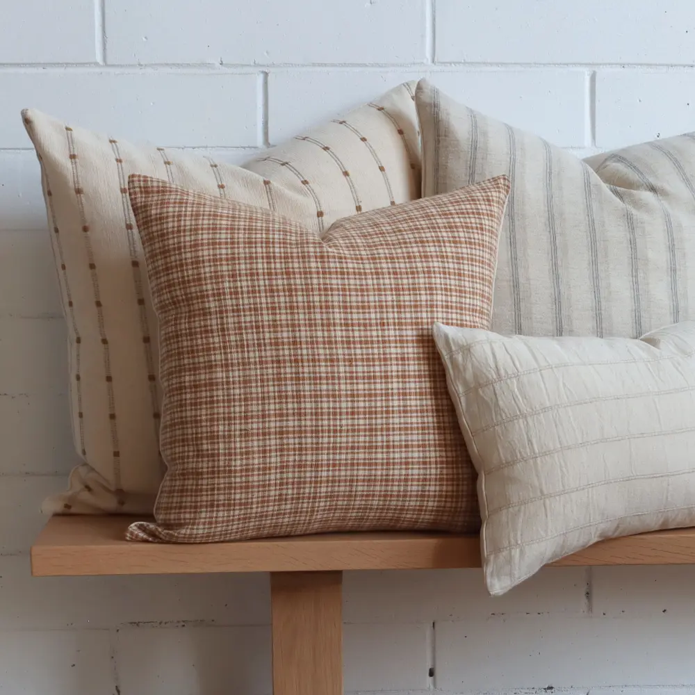 A collection of Thai woven designer cushions on a bench made of wood.