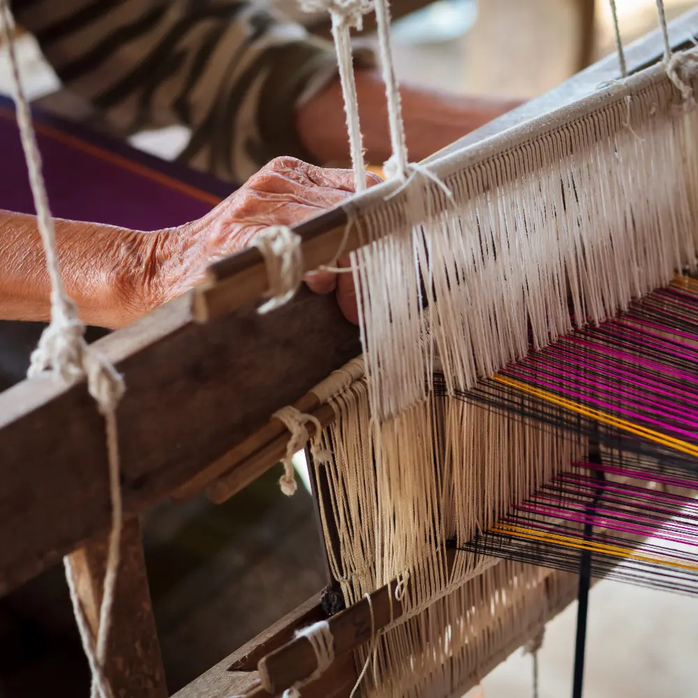 Traditional Thai woven fabric being made on a wooden loom.