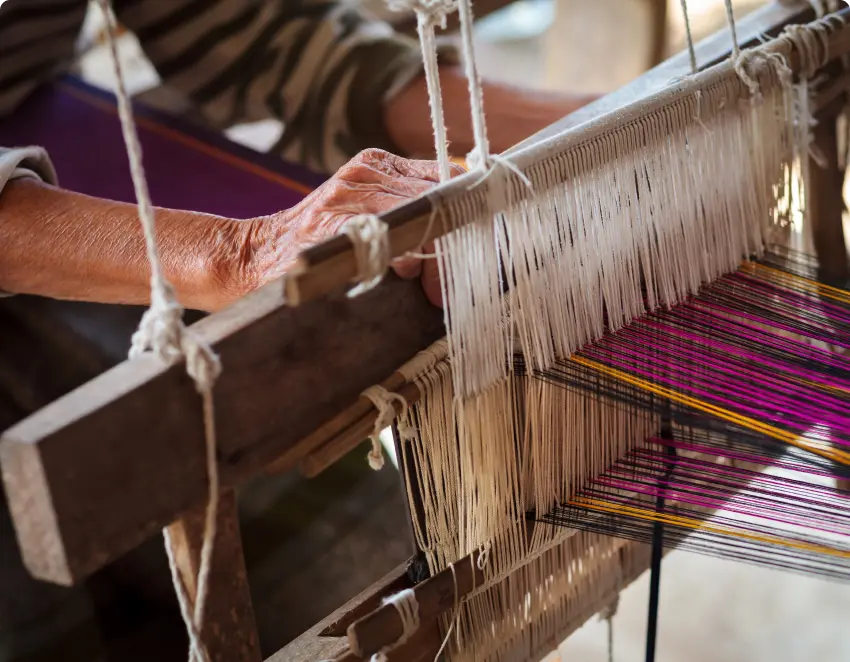 A wooden hand loom is being used by a lady from a hill tribe to make textiles.