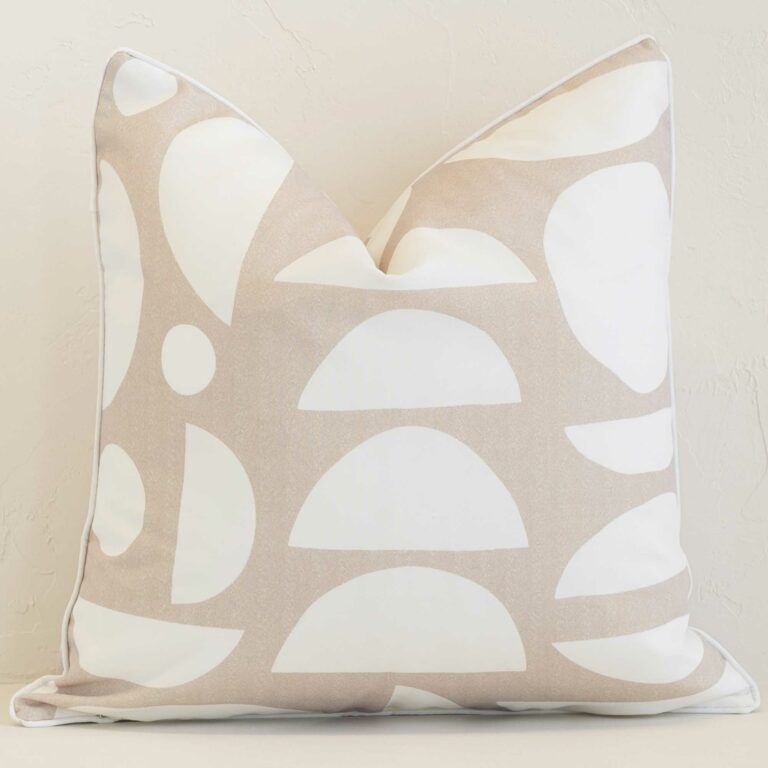 Sand geometric cushion cover in front of a white wall. It has a square shape and is made from an outdoor material.