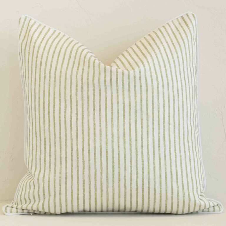 An attractive striped outdoor cushion in front of a white brick wall. It has a square shape and is sage in colour.