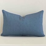 Blue outdoor cushion cover features prominently against a white wall. It is a rectangle design and has a solid-coloured decorative finish.