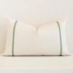 A pretty striped outdoor cushion cover is shown against a brick wall. It features a rectangle shape and a cream colour finish.