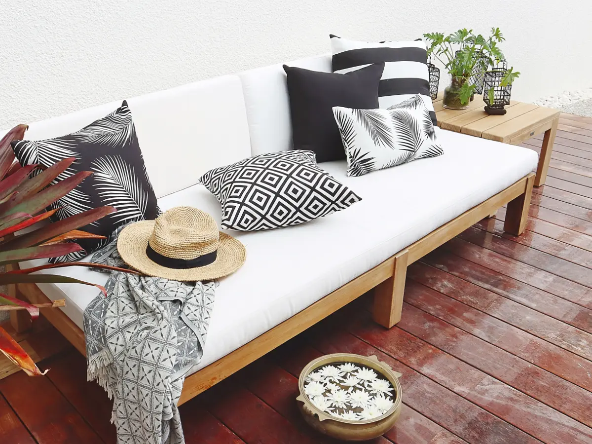 Multiple black and white outdoor cushions arranged on a light coloured outdoor couch.