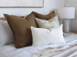 A striking cushion combination is positioned on a bed a features various tones of brown colours.