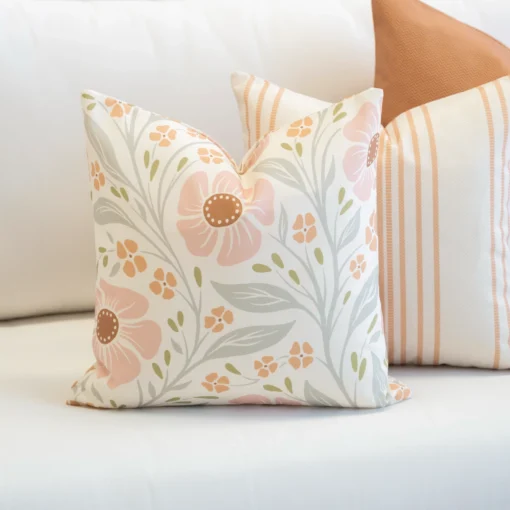 A set of 3 desert bloom outdoor couch cushions are tucked in the corner of a white sofa.