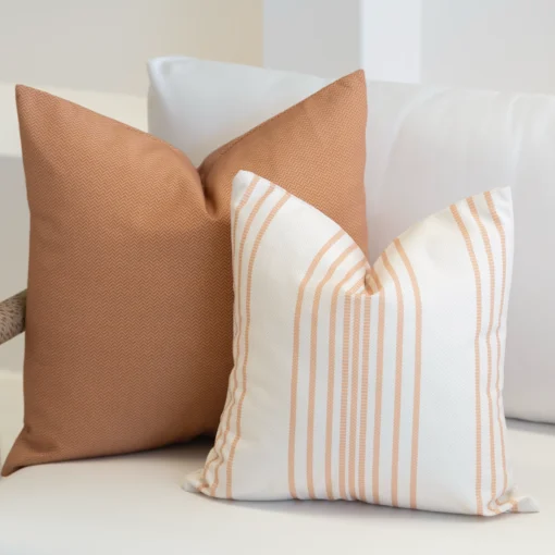 Desert bloom coloured outdoor cushions are displayed in the corner of a white sofa.