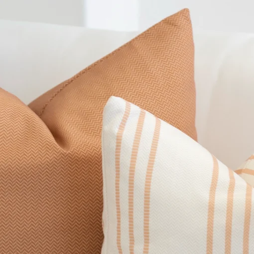 Corner of a set of 2 desert bloom outdoor couch cushions in a white living room.