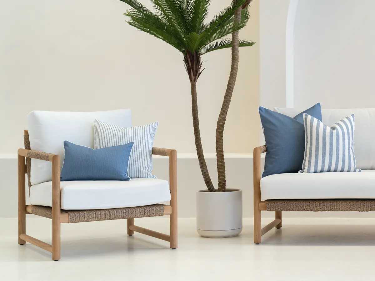 An outdoor armchair and an outdoor couch are styled with coordinated blue designs.