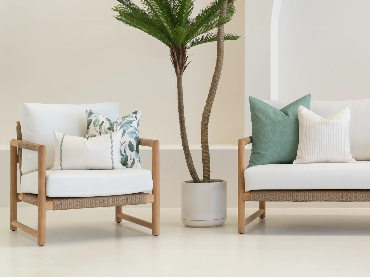 An outdoor setting with two chairs styled with sage outdoor cushions in various stripe and print designs.